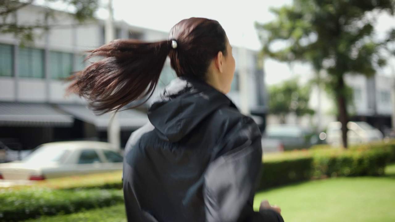 漂亮迷人的女人穿着运动服在公园里跑步。健康的女人慢跑在户外在村庄。在早上锻炼。健康积极的生活方式理念。视频素材