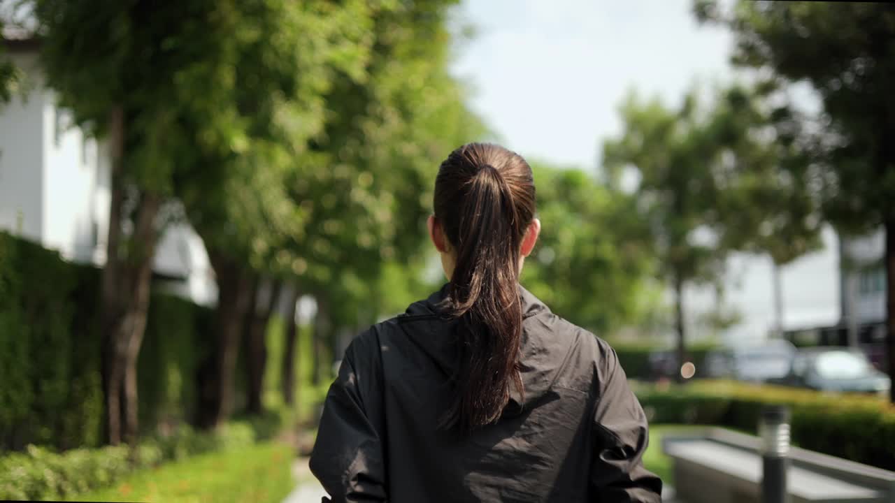 漂亮迷人的女人穿着运动服在公园里跑步。健康的女人慢跑在户外在村庄。在早上锻炼。健康积极的生活方式理念。视频素材