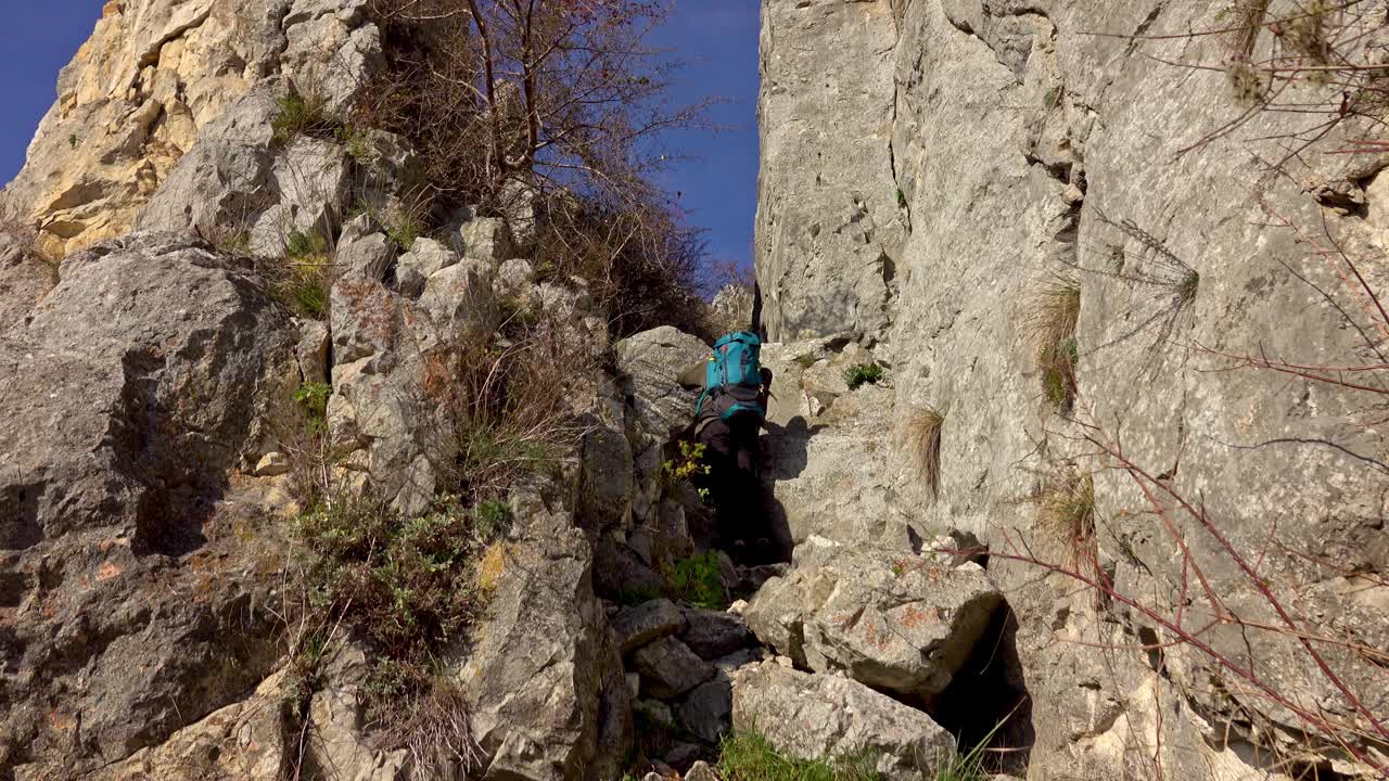 徒步旅行者沿着陡峭的碎石地形到达山顶视频素材