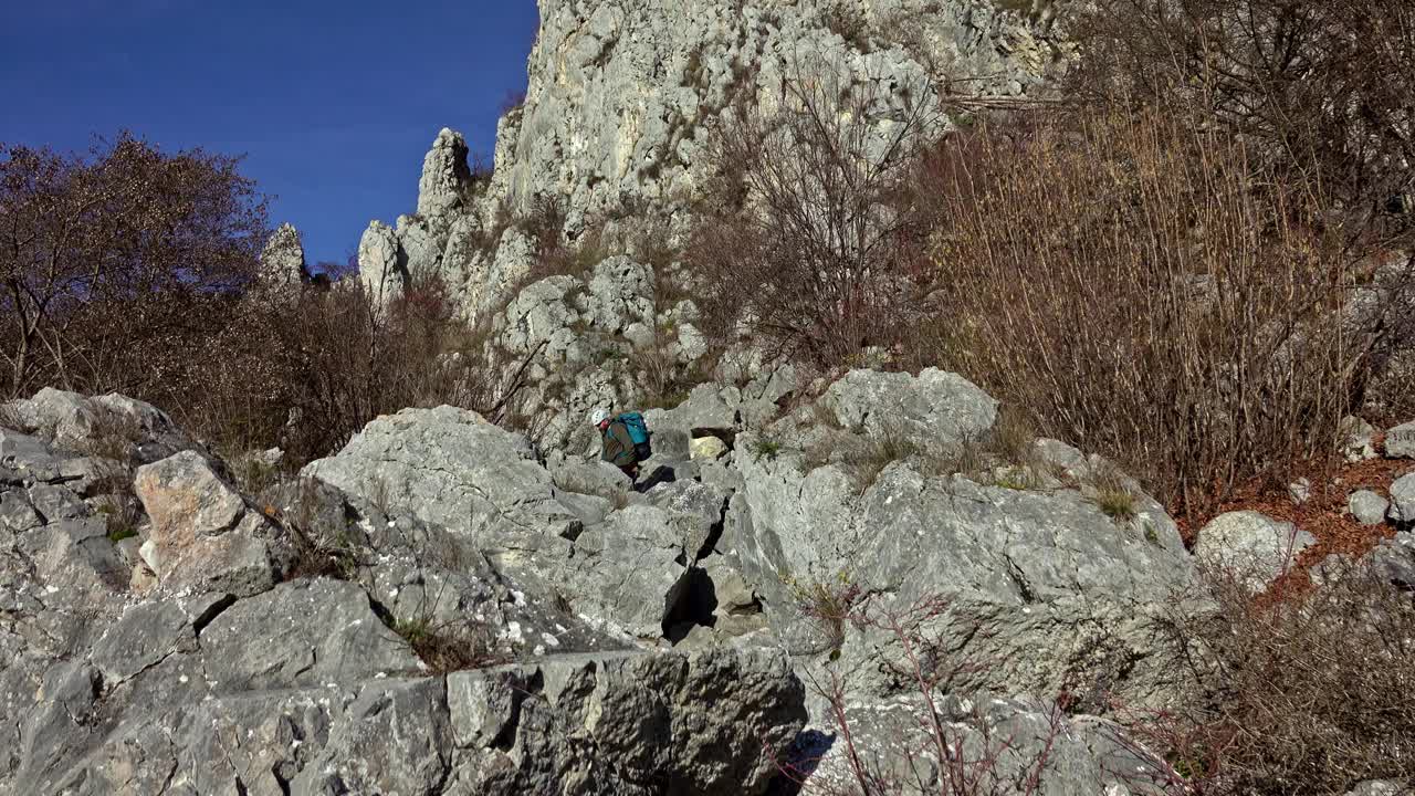 徒步旅行者沿着陡峭的碎石地形到达山顶视频素材