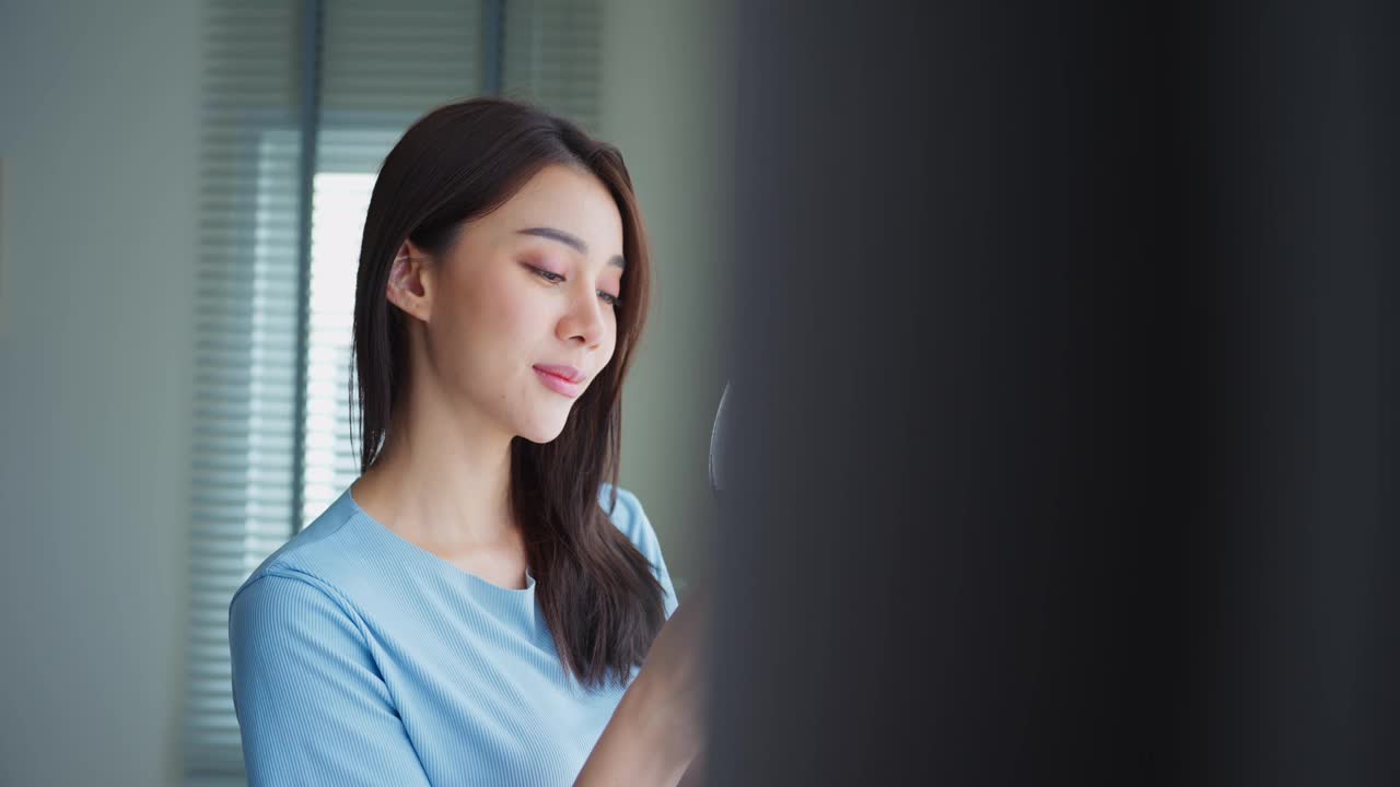 亚洲美女独自站在客厅喝酒。迷人的年轻女孩拿着一杯酒，心情愉快，放松地庆祝节日周末活动在家里。视频素材