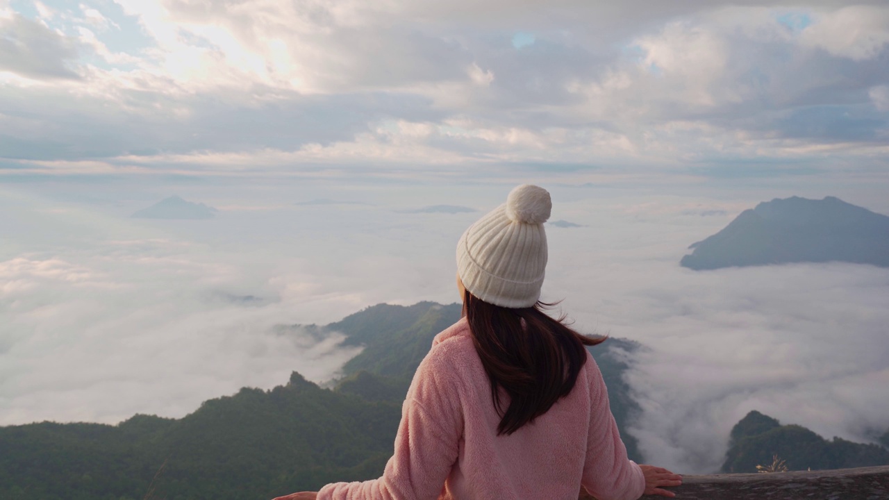 年轻女子旅行者在清晨的山上看日出和雾海，旅行的生活方式概念视频素材