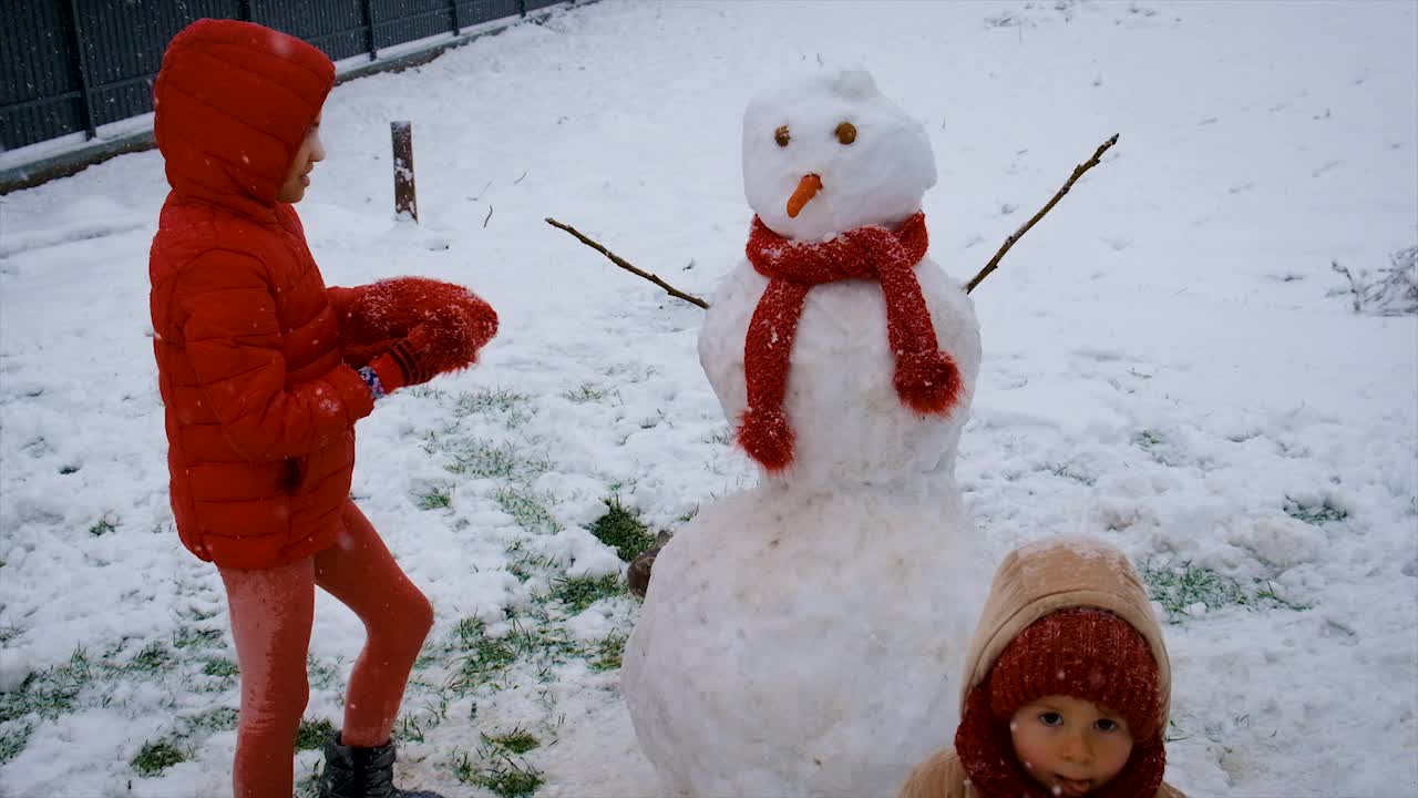 孩子们用雪堆雪人。有选择性的重点。冬天视频素材