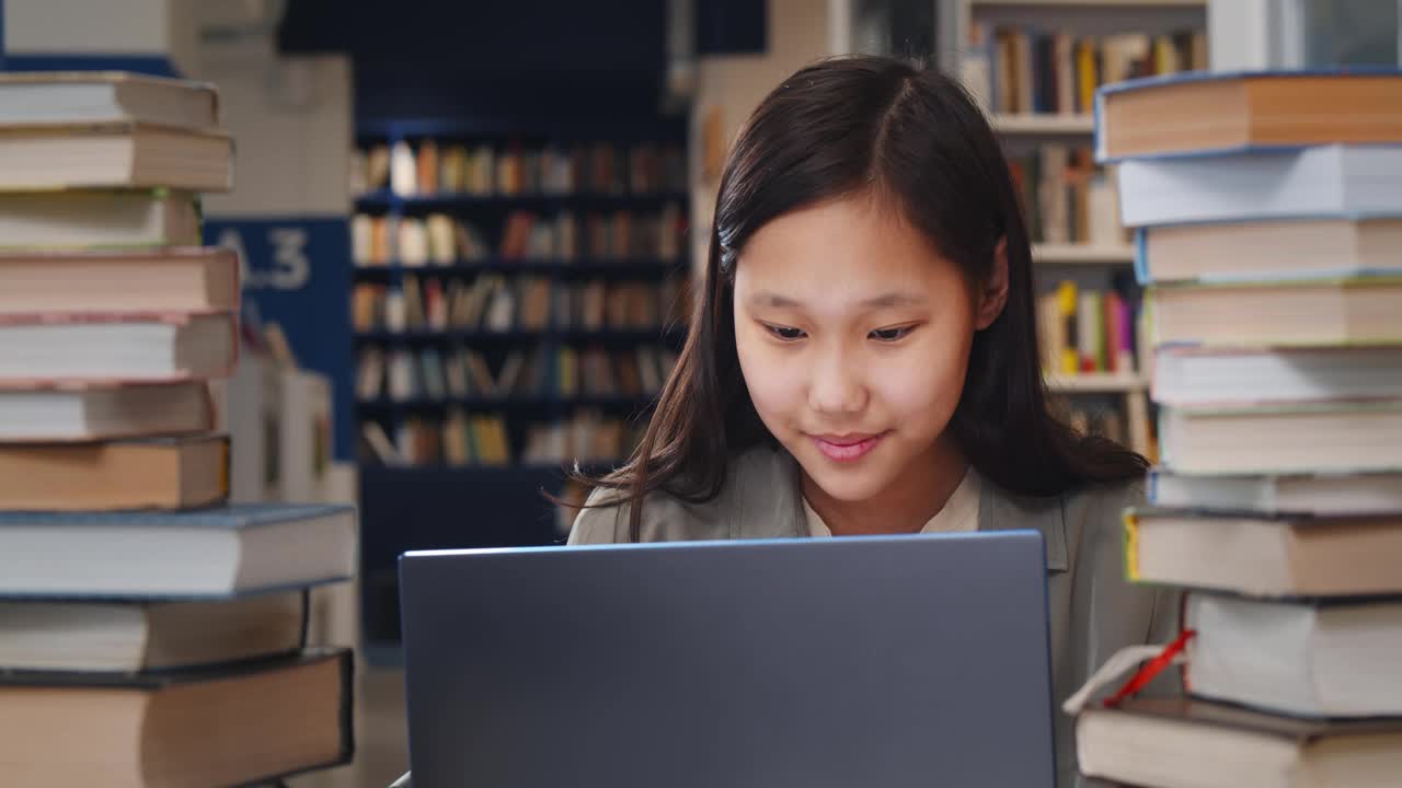 亚洲女学生在笔记本电脑上学习，微笑着坐在学校图书馆视频素材