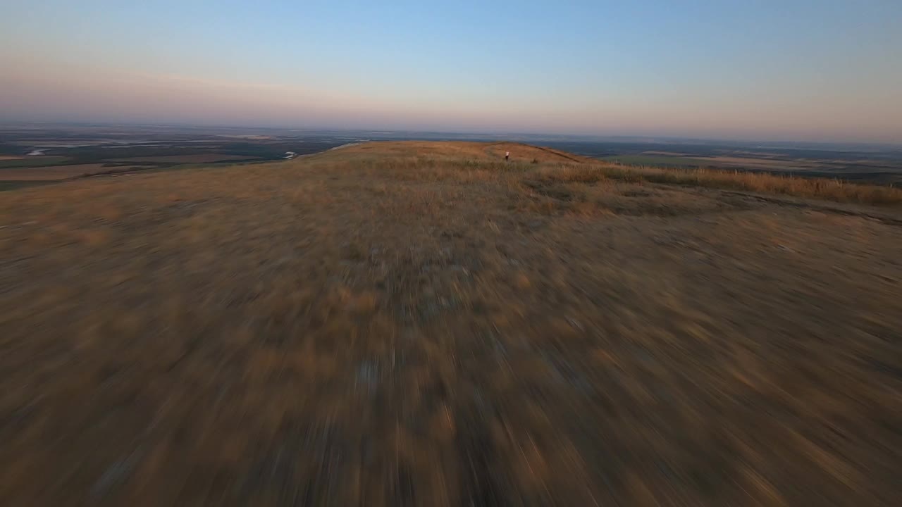 在美丽的夏日夕阳下，空中无人机拍摄的年轻健美女性在明亮的阳光下在山顶上伸展身体。视频素材