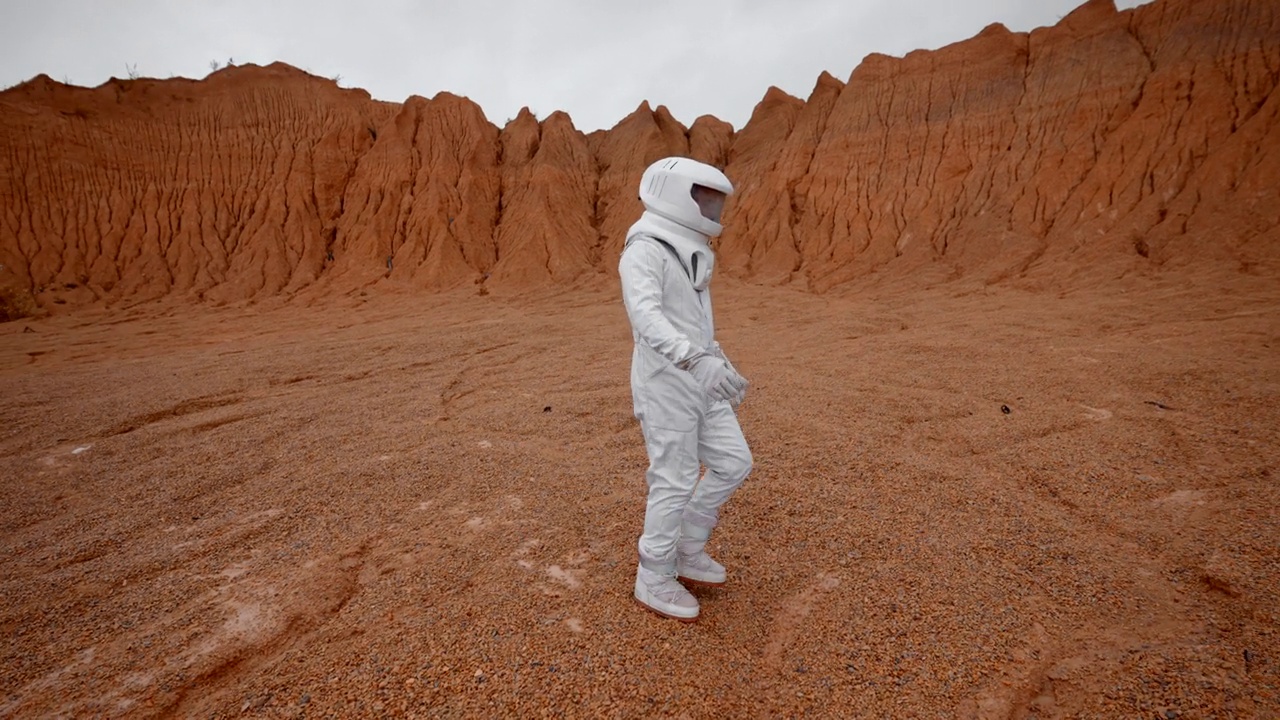 宇航员穿着一套特殊的衣服在一个无人居住的星球表面行走视频素材