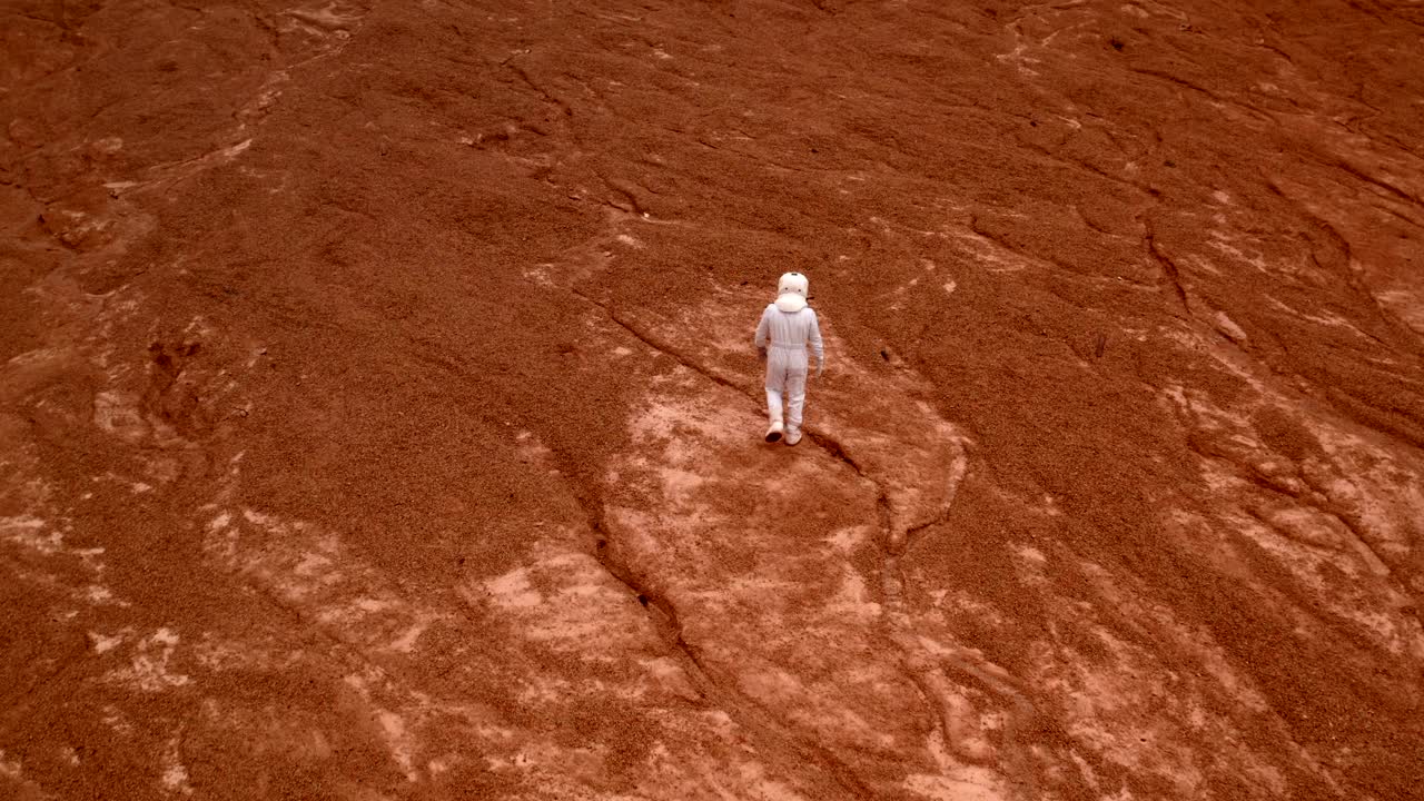 航拍的宇航员走到一个遥远星球上的火山口的墙壁视频素材