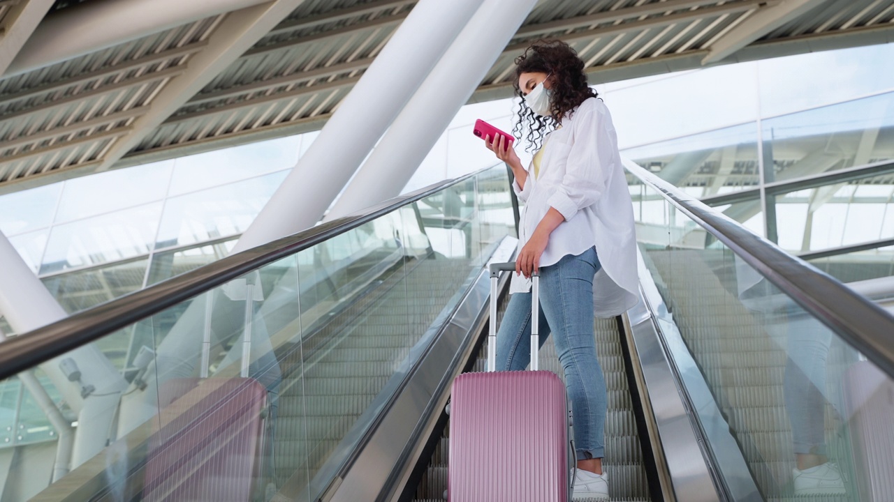 带着行李和手机的女孩旅行者在火车站的自动扶梯上视频素材