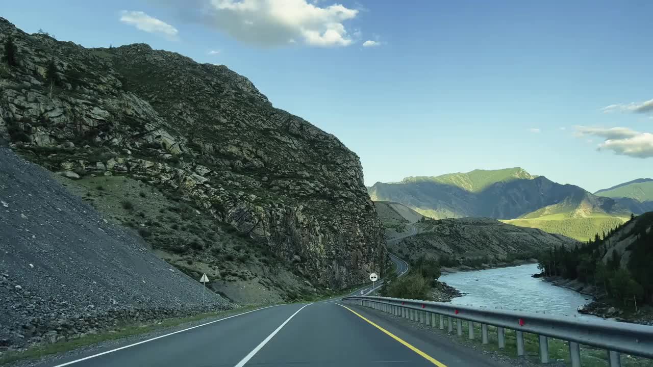 汽车正沿着西伯利亚青山间的一条蜿蜒的山路行驶。视频素材