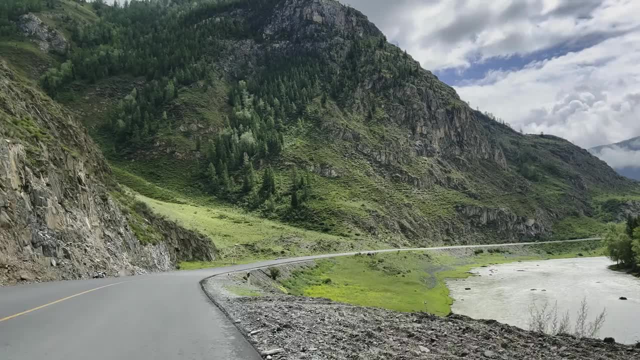 汽车沿着河流蜿蜒的山路行驶。视频素材