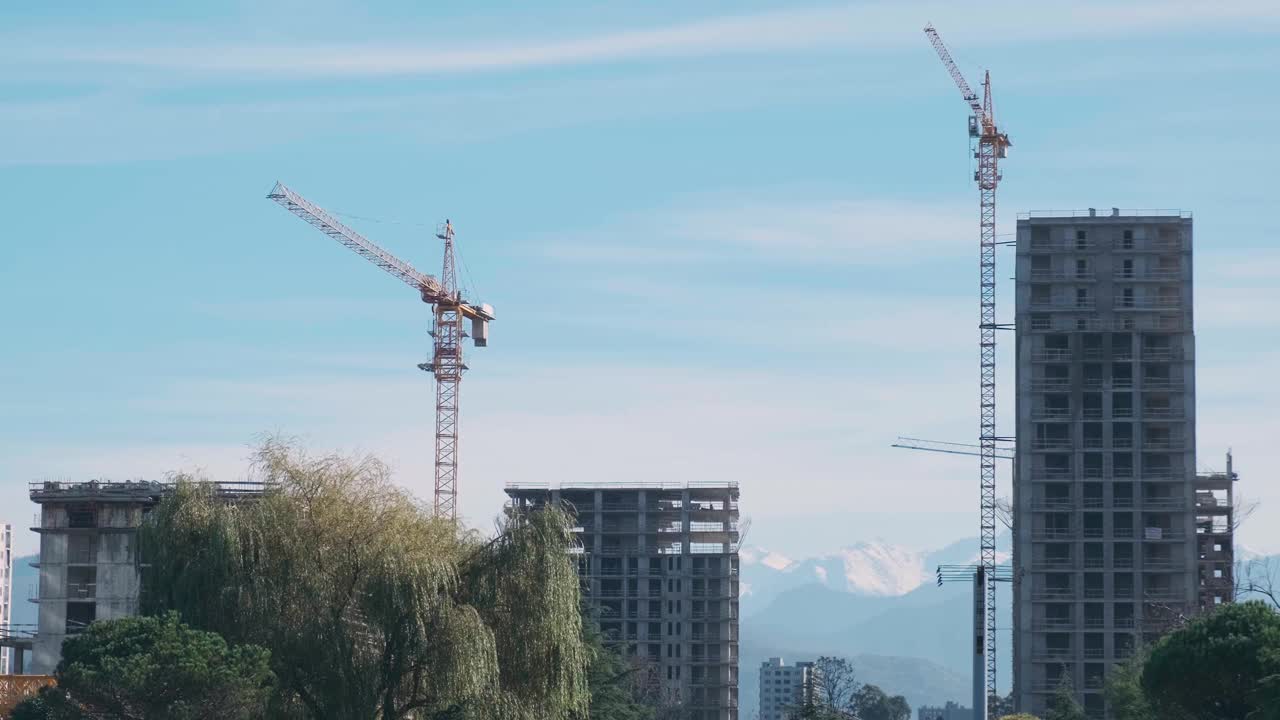 建筑起重机和高层住宅公寓正在建设中，背景是山视频素材