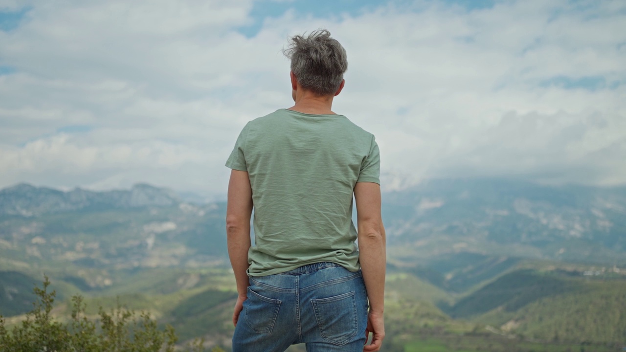 后景启发男人站在户外的山背景和举起他的手臂。男子旅行者在土耳其享受大自然和野外的美丽。旅游度假概念。视频素材