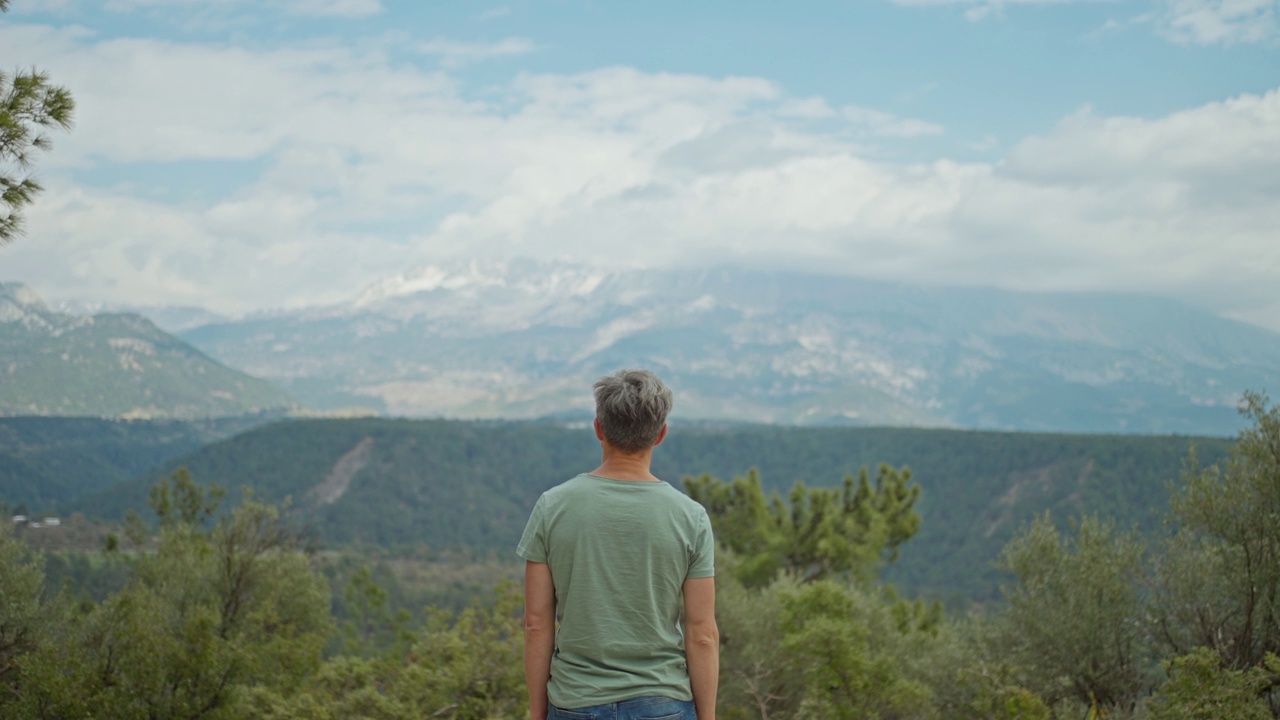 后景启发男人站在户外的山背景和举起他的手臂。男子旅行者在土耳其享受大自然和野外的美丽。旅游度假概念。视频素材