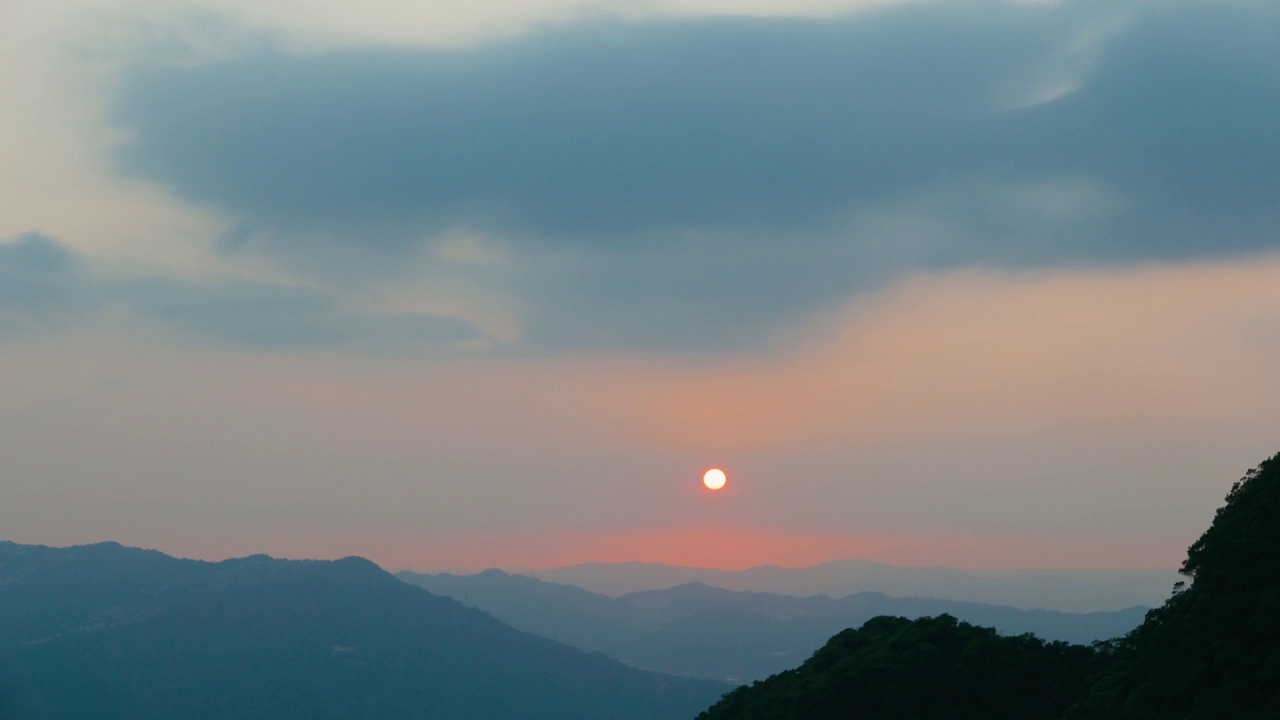 太阳落在层峦叠嶂的山后。小小的红太阳。视频素材