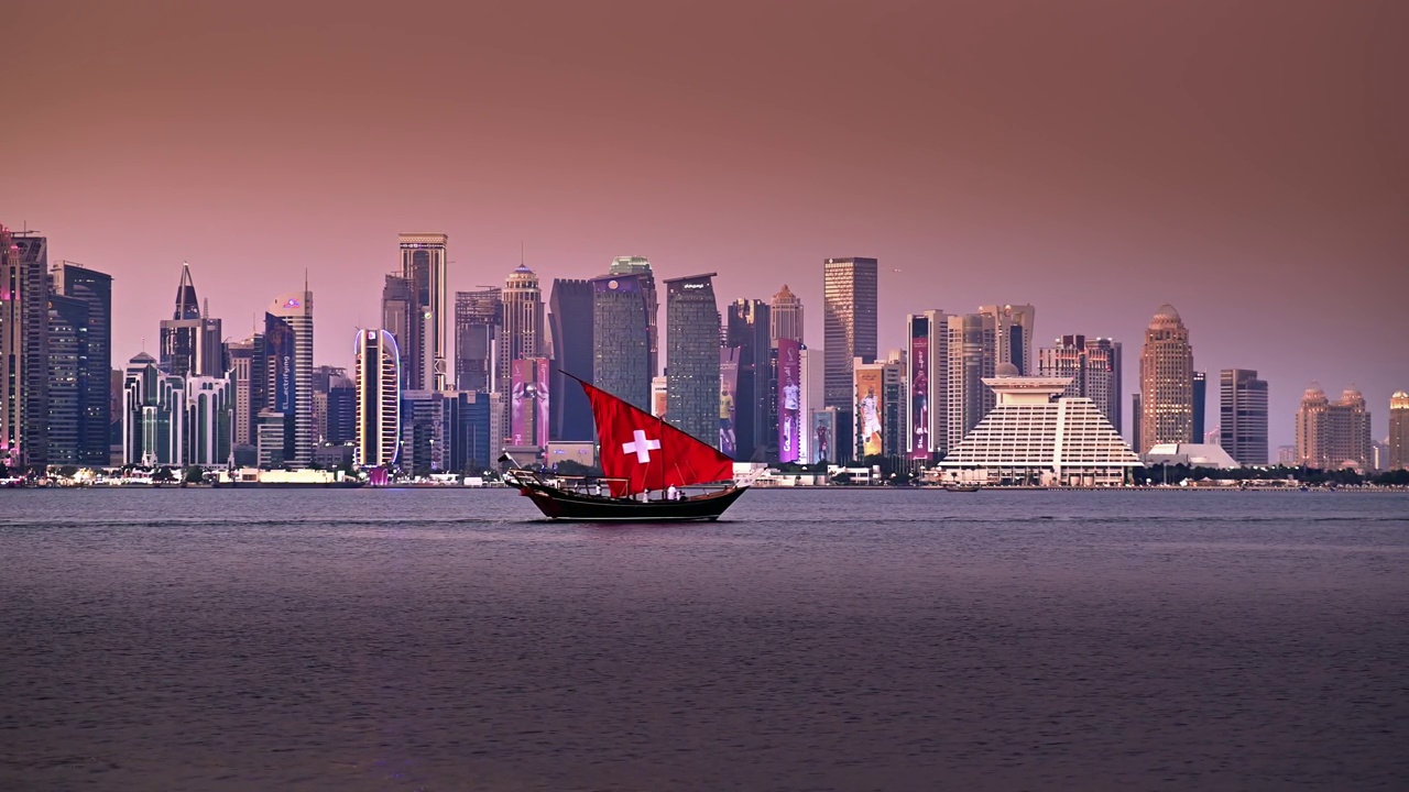 在滨海大道地区，传统的帆船与瑞士国旗设计，与惊人的城市景观摩天大楼的日落景色视频素材