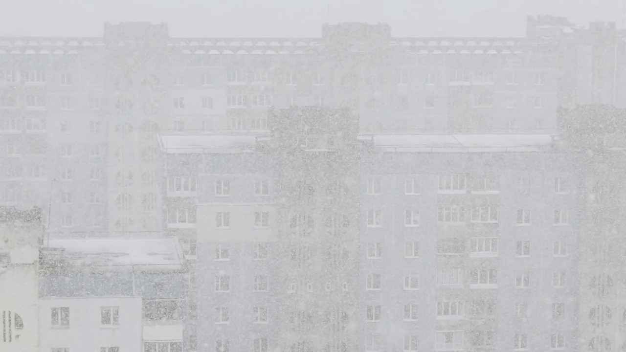 城市里有强烈的白色暴风雪。雪花在建筑物间盘旋，慢镜头。视频素材