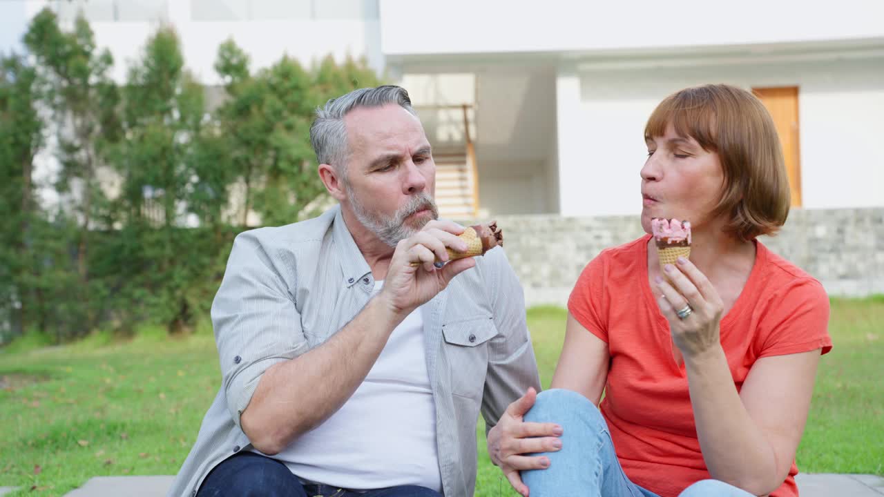 白人男子和妇女正在户外花园野餐。有吸引力的老夫妇感到快乐和放松享受退休后在公园一起吃冰淇淋的关系。视频素材