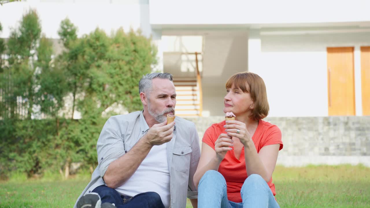 白人男子和妇女正在户外花园野餐。有吸引力的老夫妇感到快乐和放松享受退休后在公园一起吃冰淇淋的关系。视频素材