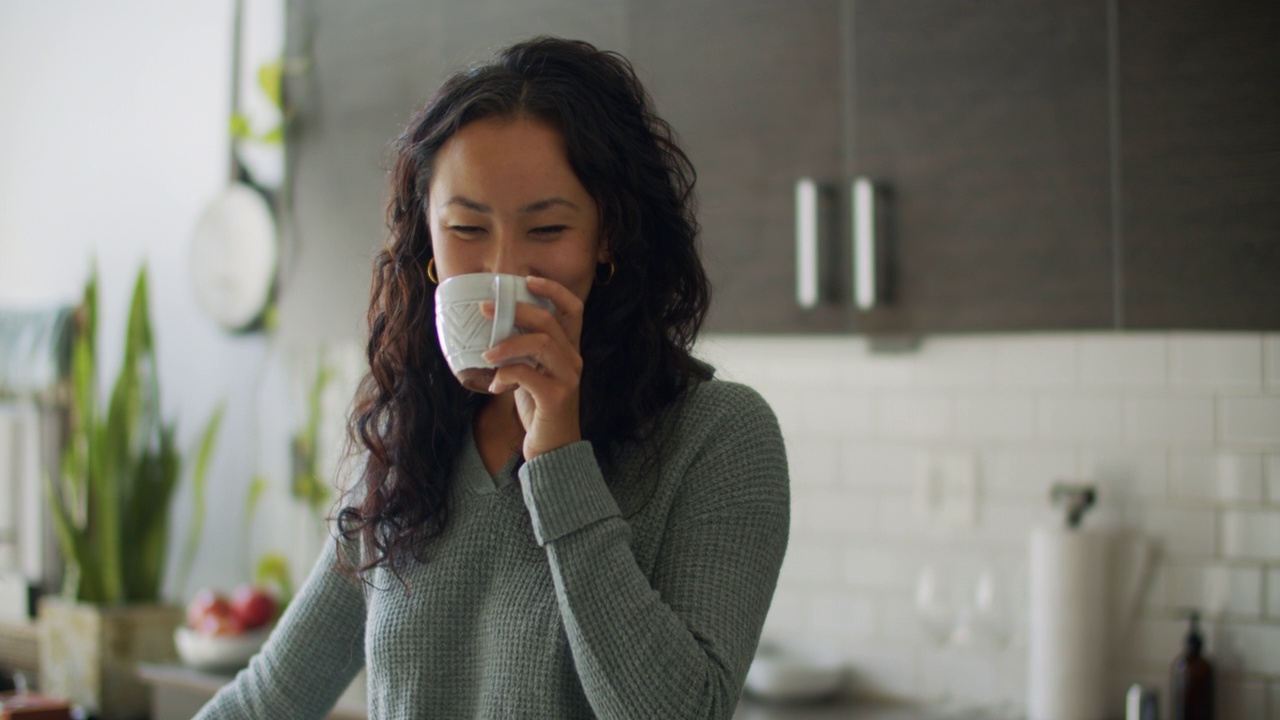 年轻女子在厨房喝咖啡视频素材