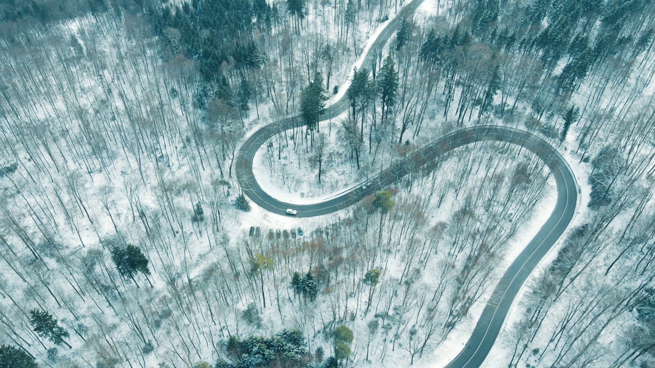 鸟瞰图的交通在蛇形的积雪覆盖的山路视频素材