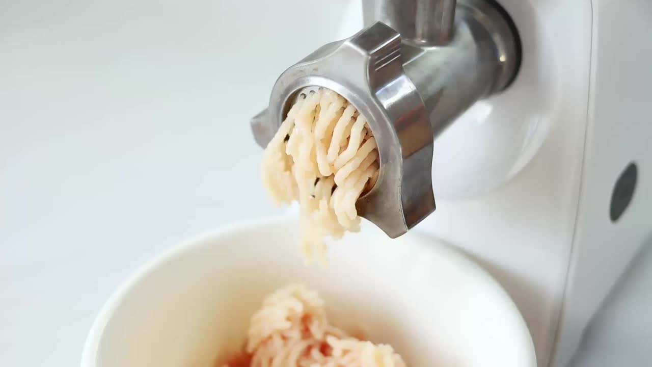 用电动绞肉机煮肉末。在电动绞肉机中磨肉的过程特写。厨房电器。慢动作视频素材