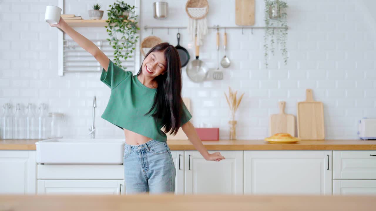 亚洲年轻女子在厨房跳舞。女性在周末空闲时间快乐放松视频素材