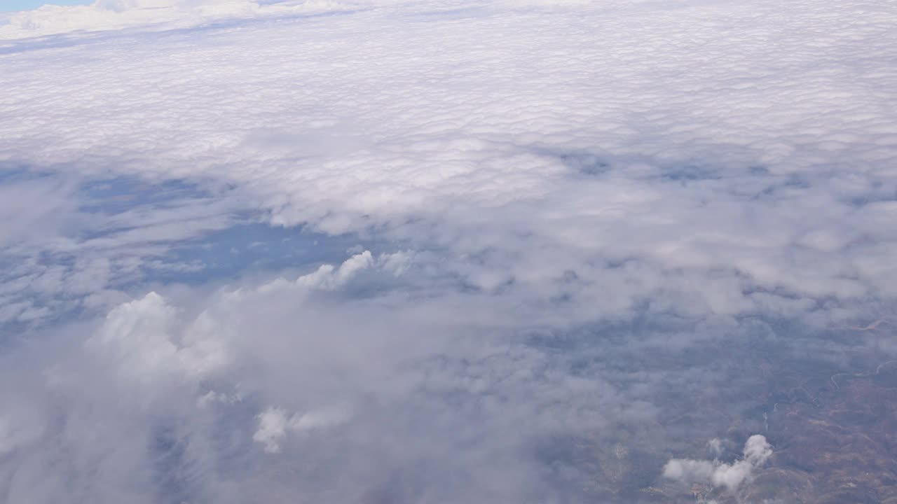 从飞机的窗户望出去，蓝天白云映衬着美丽的陆地自然景观视频素材