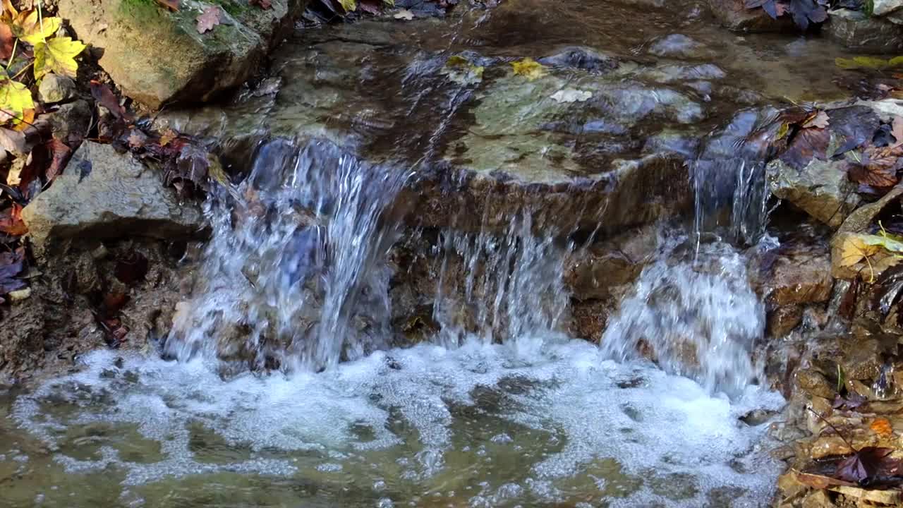 飞溅的水从小瀑布流下的慢动作视频素材