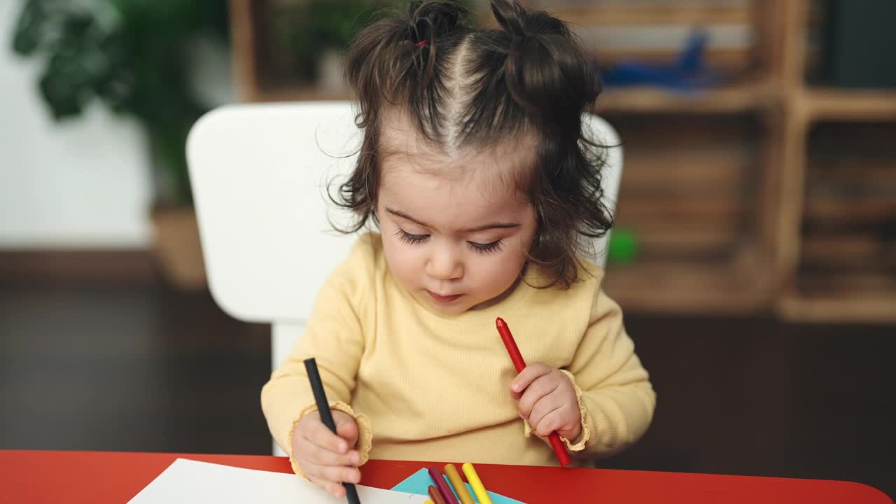 可爱的西班牙女孩学生坐在桌子上画在纸上幼儿园视频素材