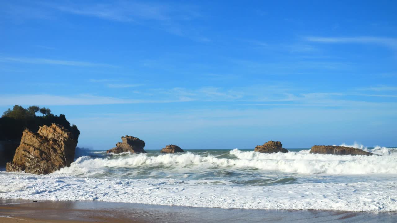 在巴斯克地区的比亚里茨海滩，海浪拍打着岩石视频素材