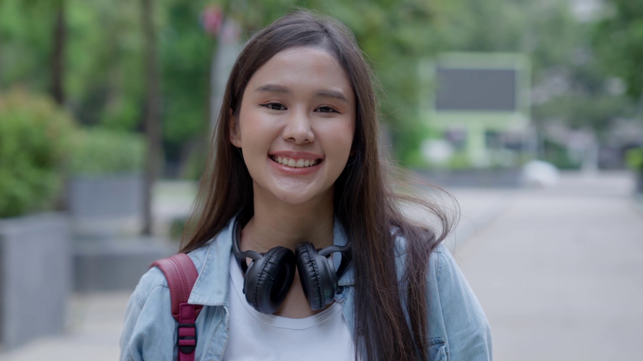 美丽的学生亚洲女人背着背包和书在户外。微笑的女孩快乐地背着很多书在大学校园。画像女上国际亚大。教育，学习，学校视频素材