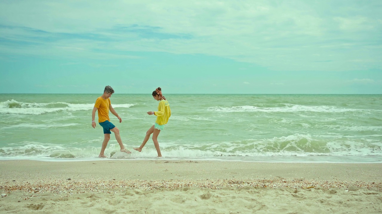 浪漫的情侣在海边玩浪，嬉笑风生。男人温柔地拥抱着女人。户外的爱和幸福的概念。视频素材