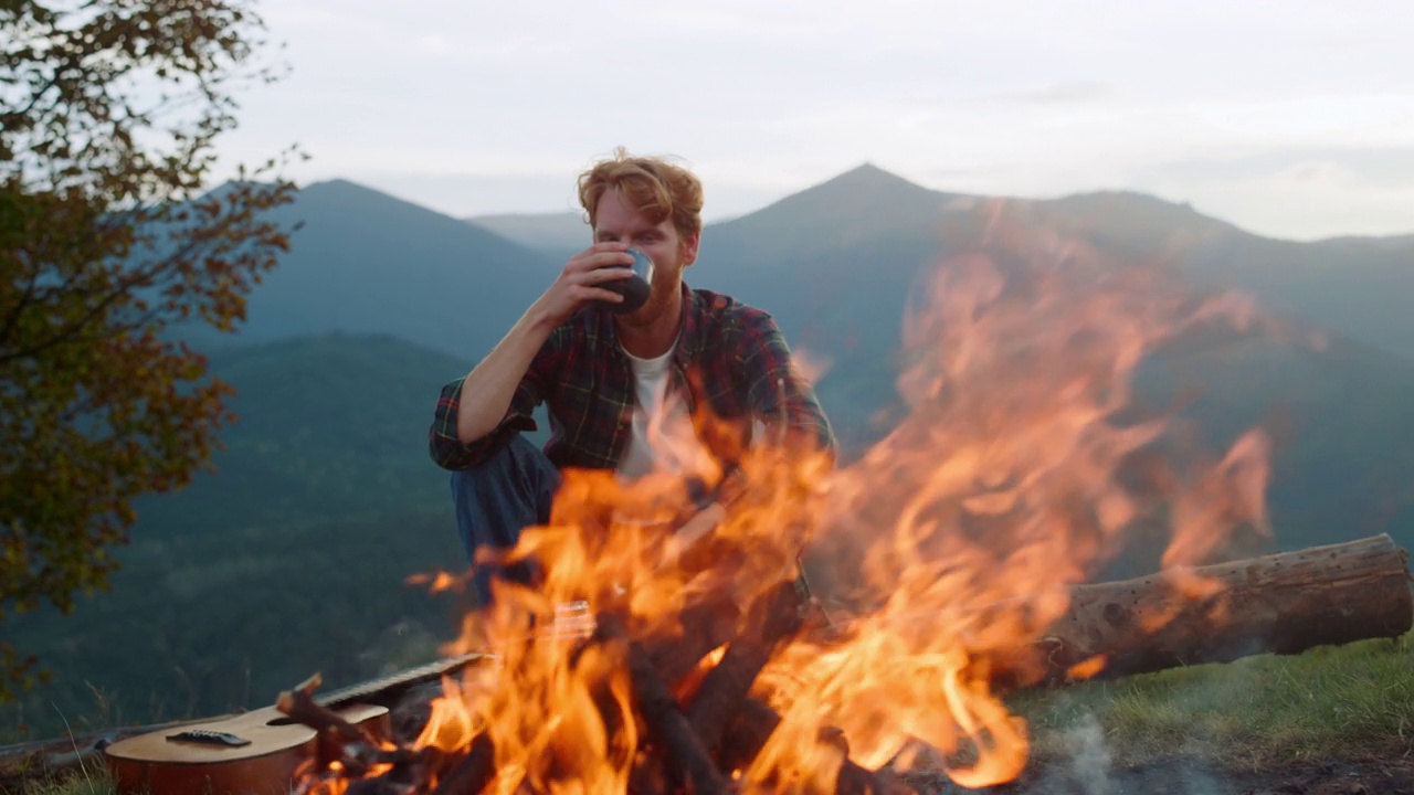 旅行者在大自然的营火上休息。无忧无虑的小伙子在外面享受山夜视频素材