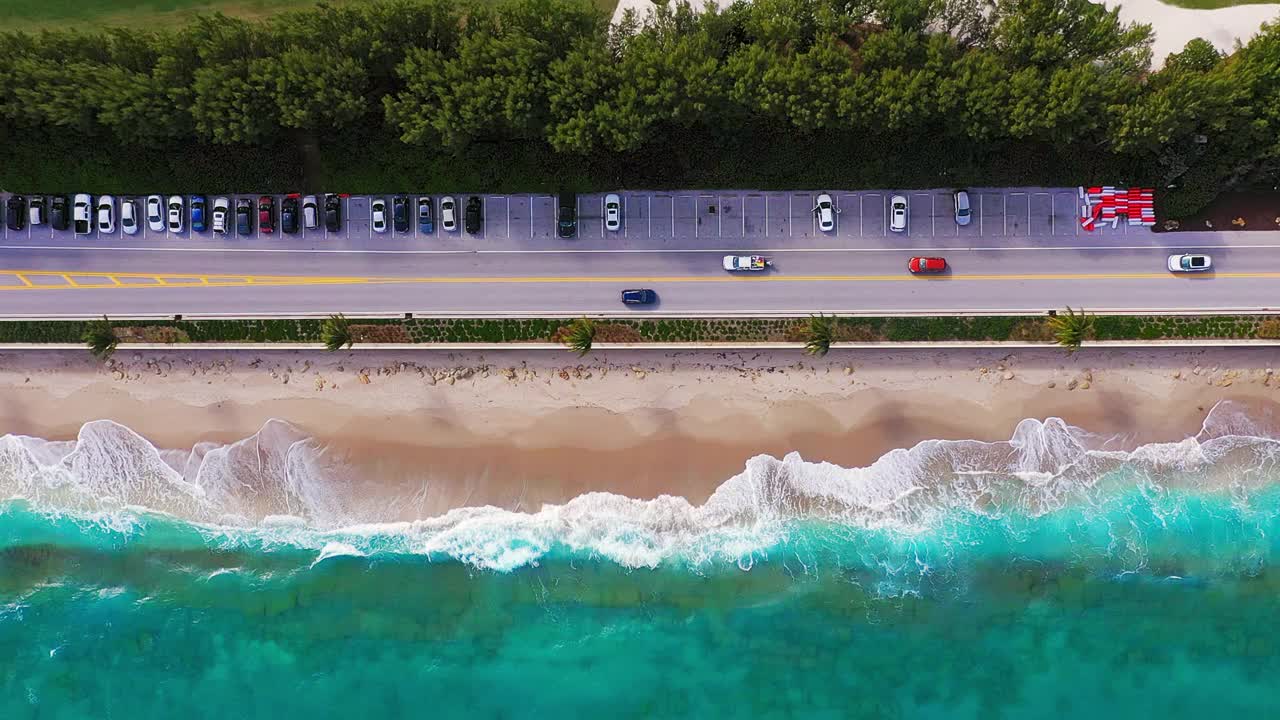 直接在空旷的白色沙滩海岸线上，热带海岸上有棕榈树，有公路和停车场视频素材