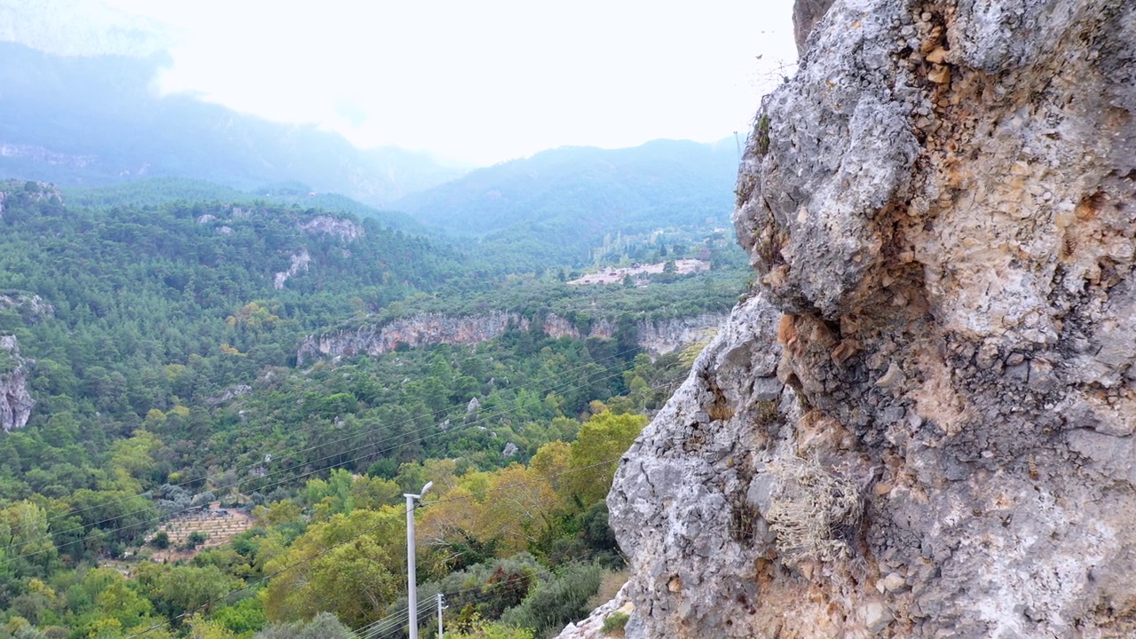 岩石峭壁的背景是绿色的山谷。乡村道路上的风景岩石形成。视频素材