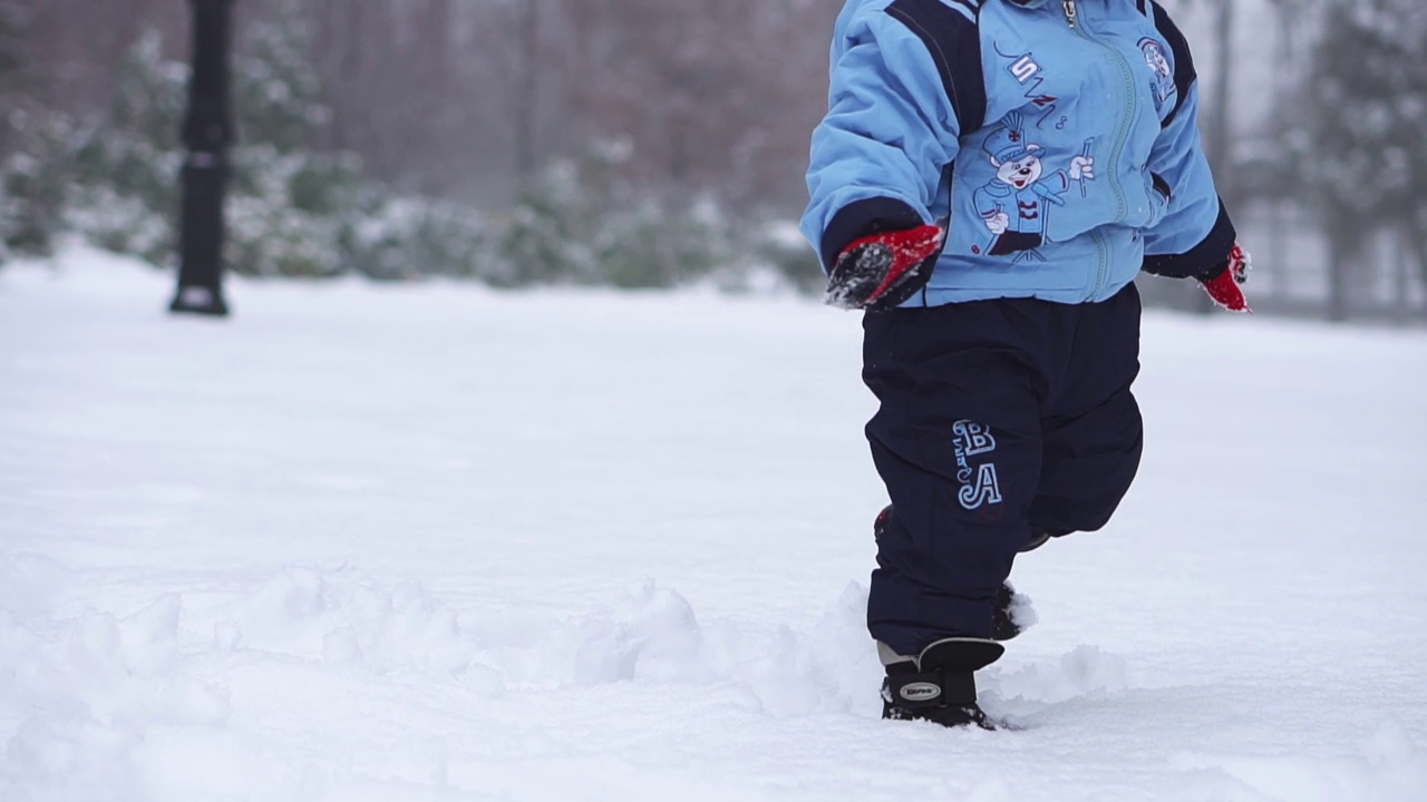 一个小男孩正在街上用手雕刻大雪球。冬季视频素材