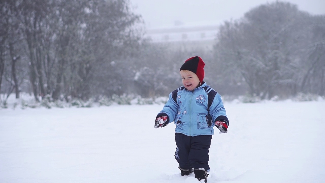 孩子微笑着走在雪地里。冬天的散步。冬天里快乐的孩子。视频下载