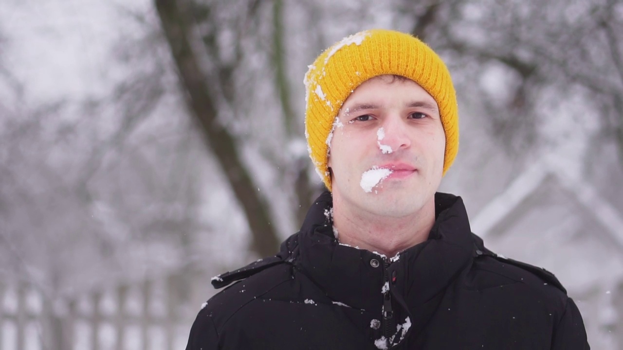 一个雪球打在一个人脸上的慢动作。冬天的乐趣。一家人在玩雪球。视频素材