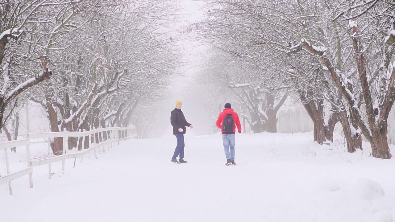 两个男人一起走在冬天的路上。在雪地里嬉笑嬉戏视频下载