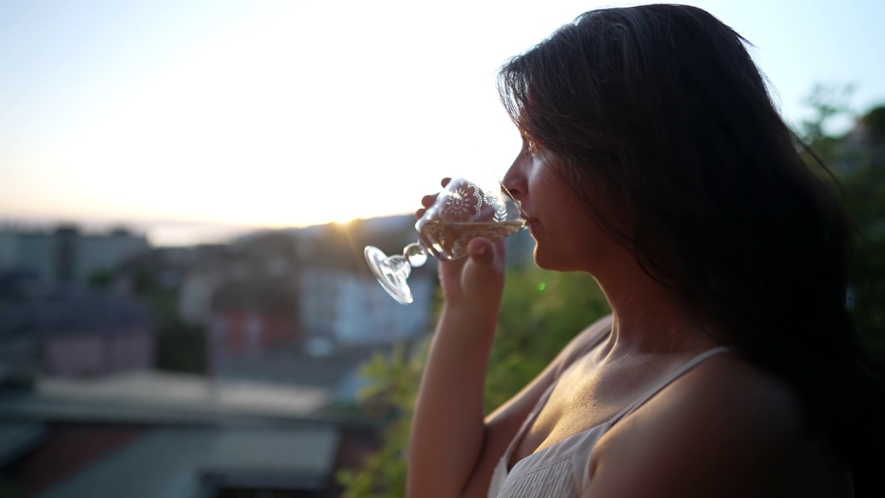 日落时分，女人在外面喝白葡萄酒。夏日，女性在户外享受酒精饮料，欣赏风景视频素材