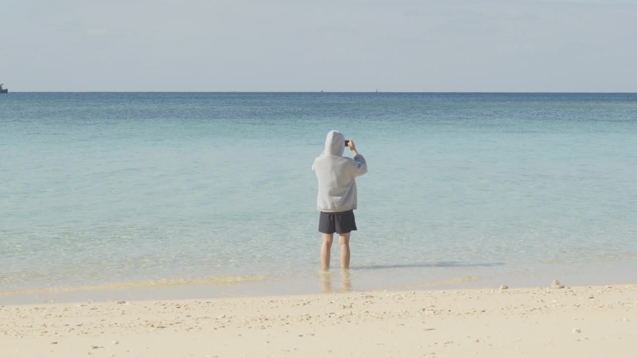 女孩在沙滩上用智能手机拍照视频素材