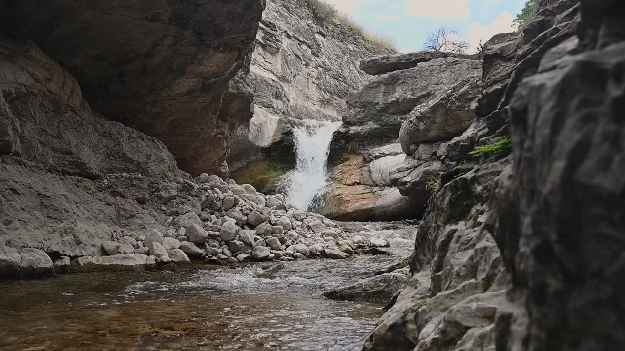 一个美丽的瀑布，在一个阳光明媚的夏日里，峡谷里有岩石和清澈的水视频素材