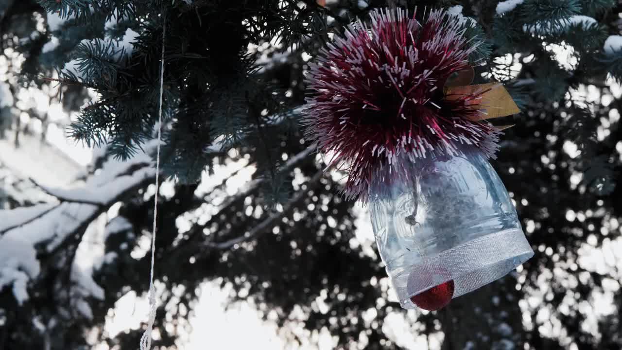 用家庭垃圾制作的自制玩具放在覆盖着积雪的圣诞树上。视频素材