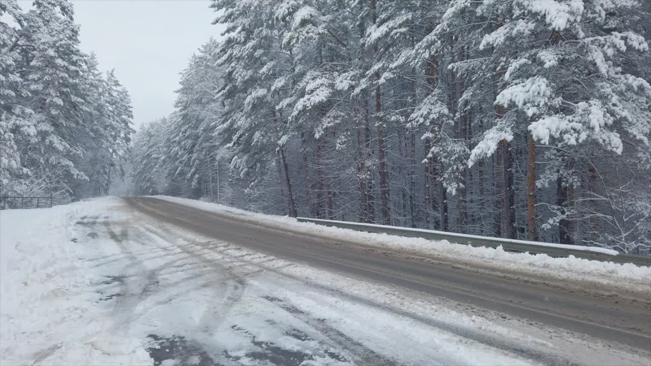 汽车在美丽的冬季森林的道路上视频素材