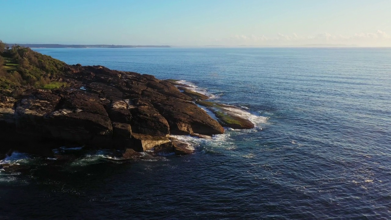 沿海岩石岬角的鸟瞰图与微妙的海浪视频素材