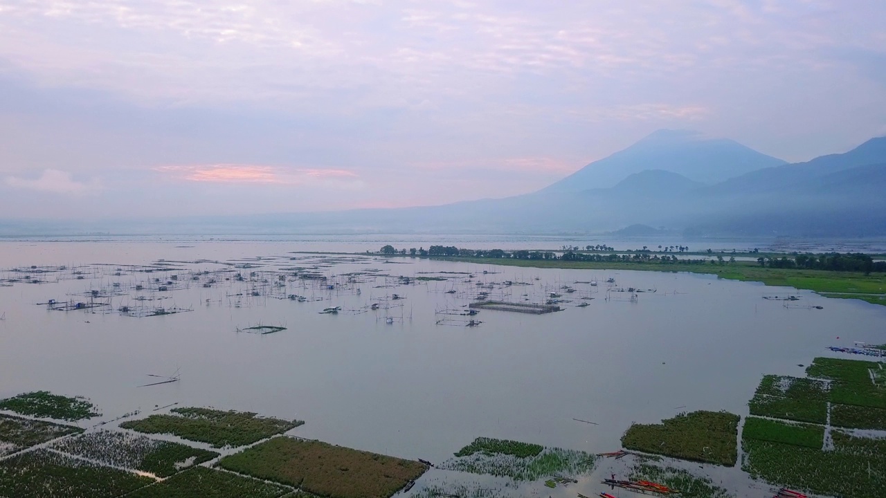 无人机拍摄的巨大湖泊与鱼笼。看到日出的天空和山的背景-拉瓦平湖，中爪哇，印度尼西亚视频素材