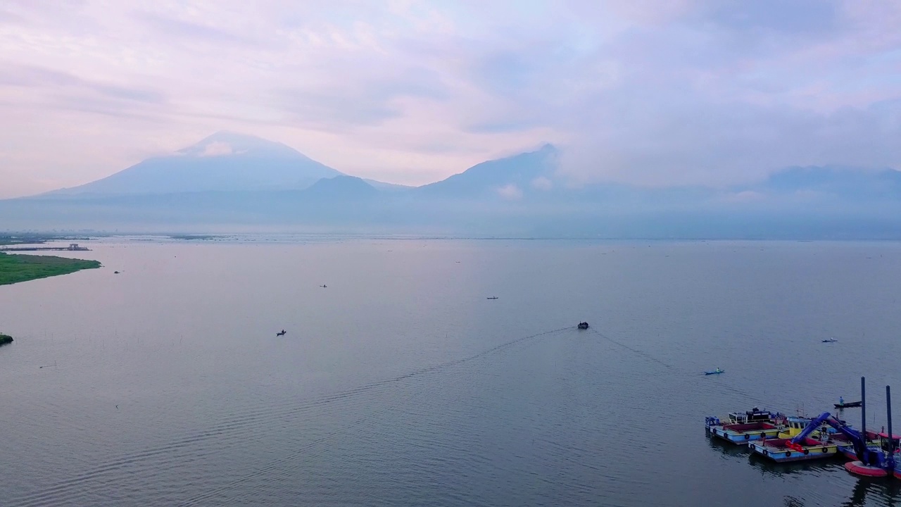 无人机拍摄的巨大湖泊与渔民船。看到日出的天空和山的背景-拉瓦平湖，中爪哇，印度尼西亚视频素材