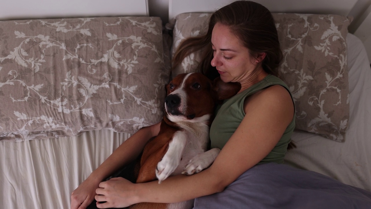 一个女人和她的三色猎犬在床上休息视频素材