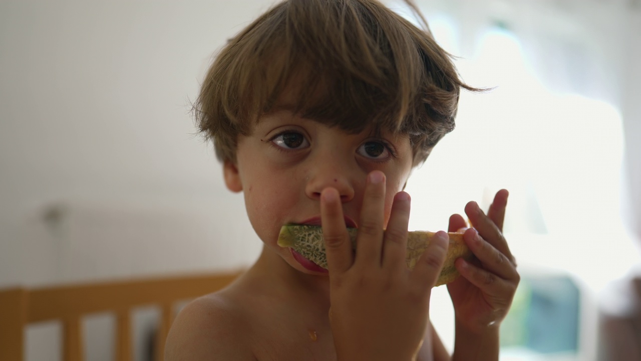 孩子咬瓜果甜点。一个小男孩正吃着健康可口的零食视频素材