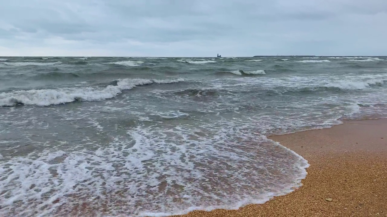 在阴天，海浪在沙滩上翻滚。视频素材